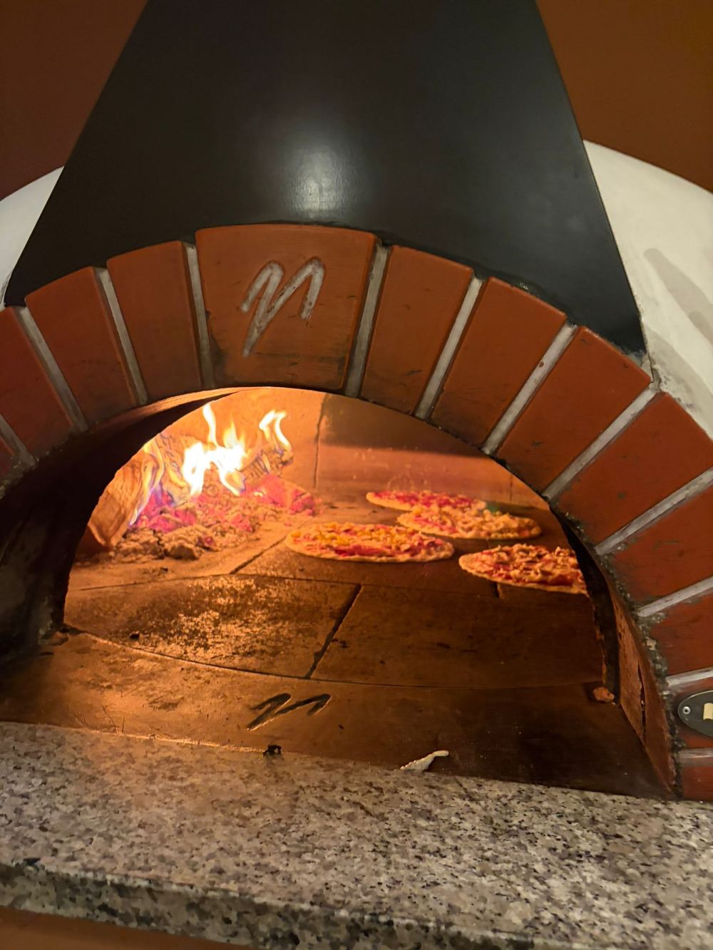 Brennender Holzofen mit Ziegelbogen im Restaurant Athen