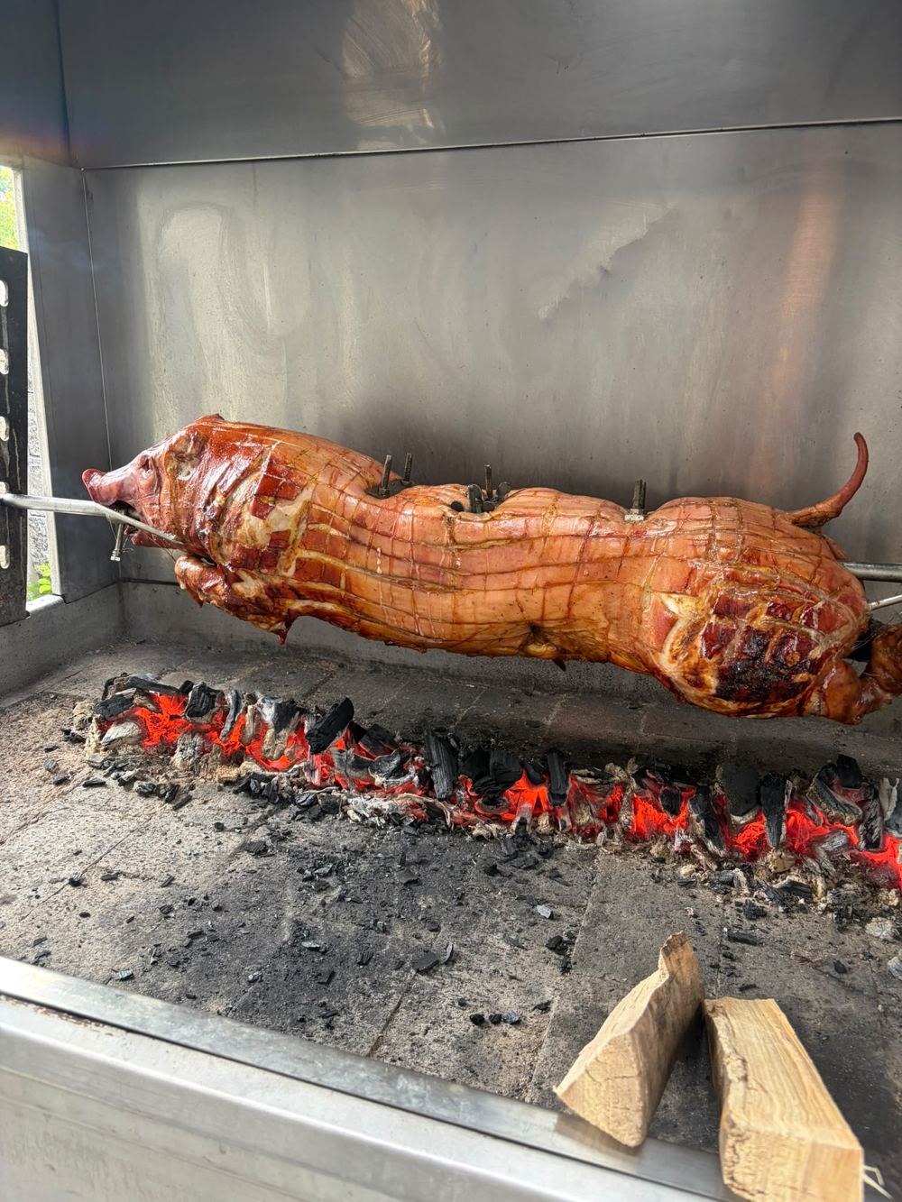 Ferkel am Drehspieß über Holzkohleglut