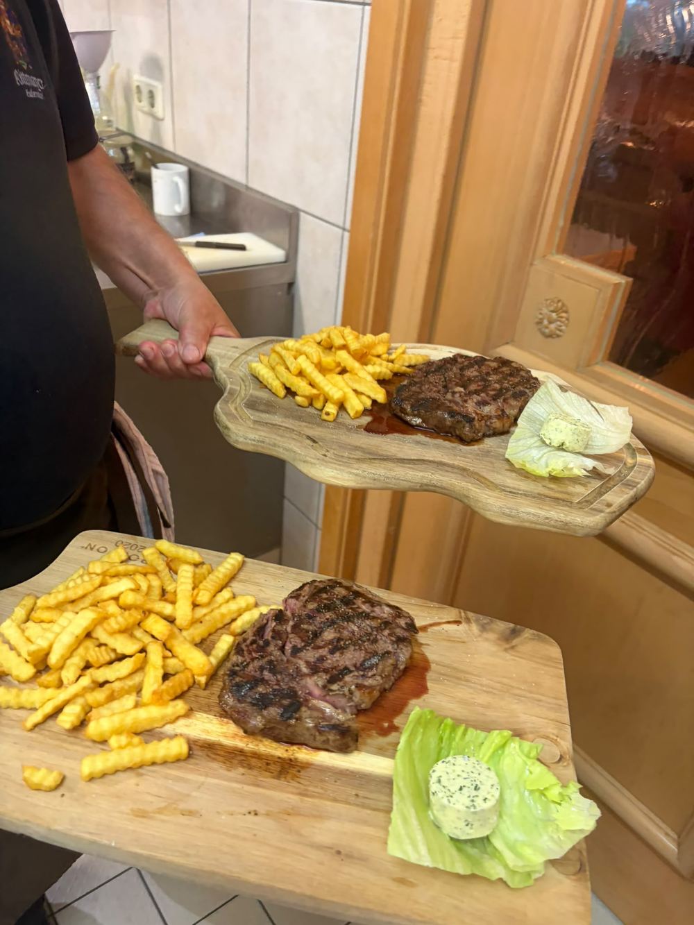 Steak mit Pommes frites und Salat auf einem Holzbrett